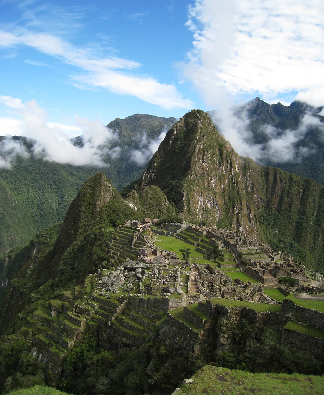 View of Machu Picchu from a short way above the site, hiking towards the Dawn Gate. This view highlights both Wayna Picchu and the spread of the city below it, both the highlights of the construction and the reinforcing terraces descending down towards the valley floor.