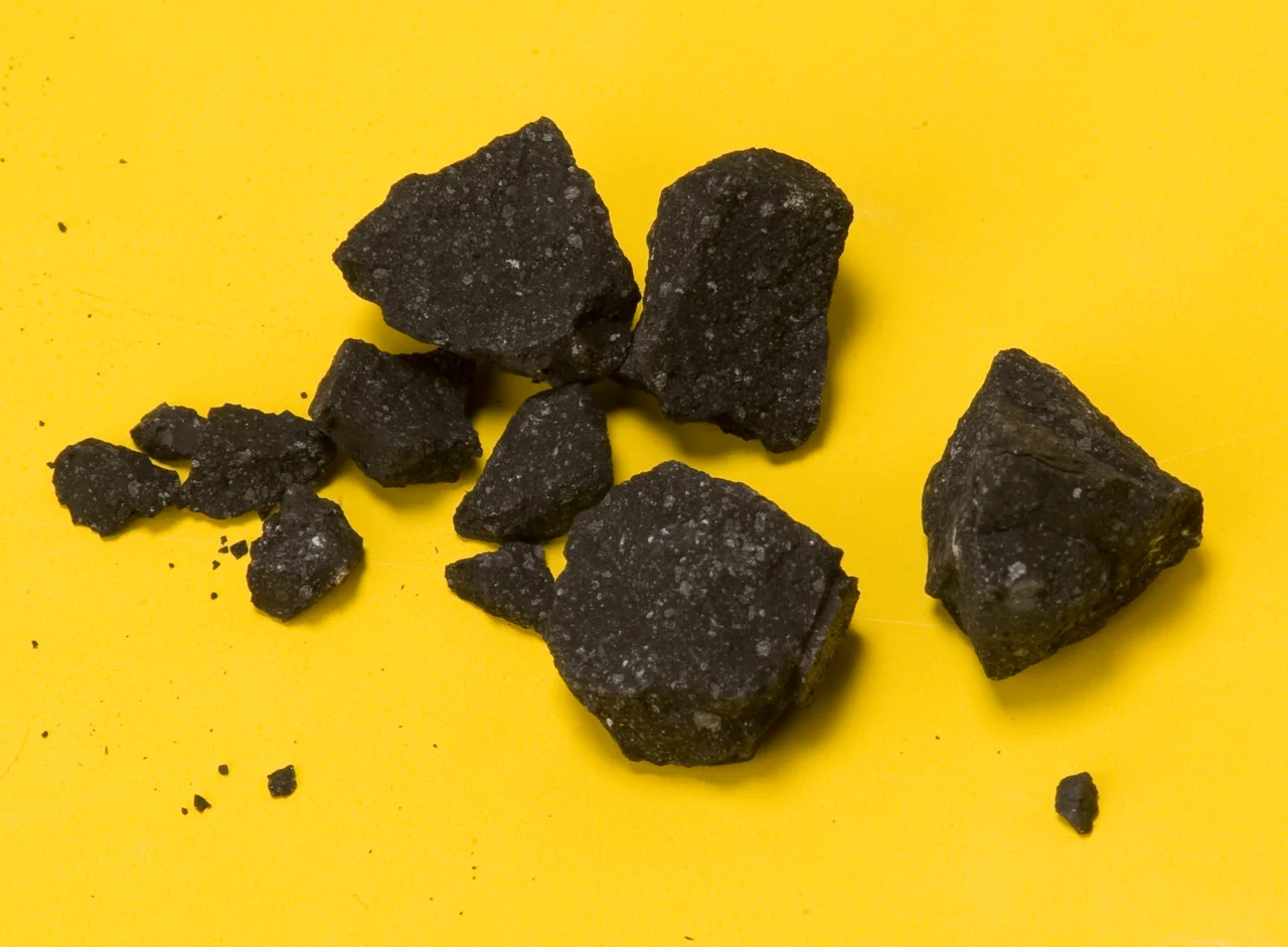 Fragments of of a crushed 4 gram meteorite (SM2) belonging to the Sutter's Mill meteorite, which is thought to be a rare CM type carbonaceous chondrite. The fragments were obtained from the parking lot of Henningsen Lotus Park in Lotus, California, near Sutter's Mill, by astronomer Peter Jenniskens. The white specks are calcium aluminium inclusions.