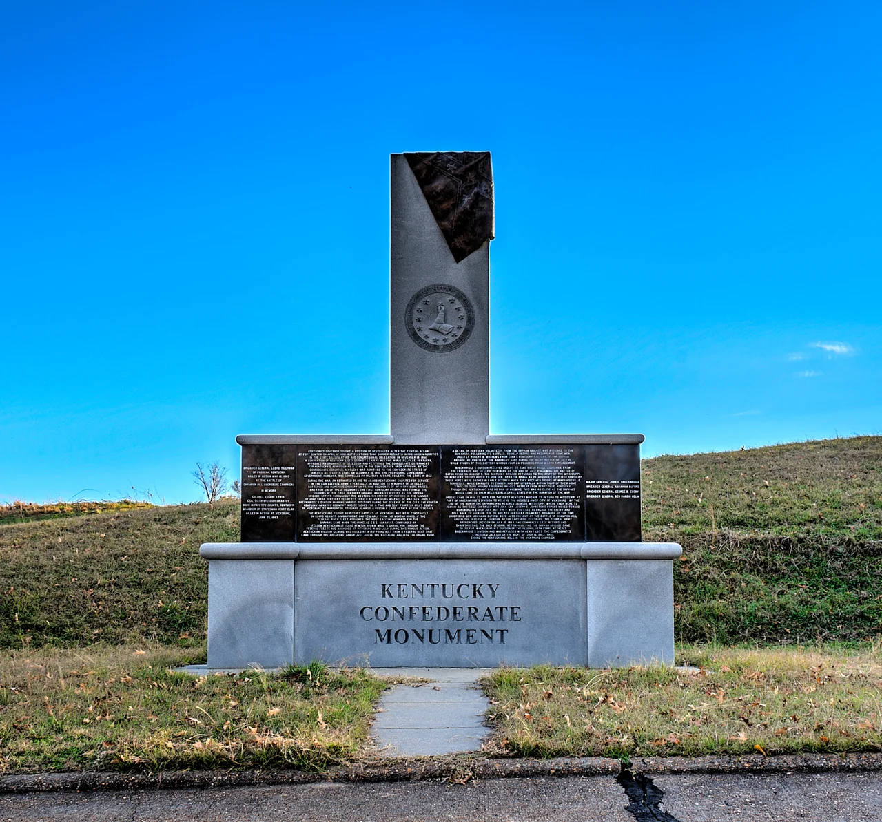 Left Panel



Brigadier General Lloyd Tilghman of Paducah, Kentucky
Killed in Action May 16, 1863 at the Battle of Cahmpion Hill (Vicksburg Campaign)


In Memory
Colonel Eugene Erwin, CSA, Sixth Missouri Infantry
Born in Fayette County, Kentucky
Grandson of Statesman Henry Clay
Killed in action at Vicksburg, June 25, 1863


Center Panels


Kentucky's governor sought a position of Neutrality after the fighting began at Fort Sumter on April 12, 1861, but elections that summer resulted in pro-Union majorities in the state legislature and congressional delegation. On November 18, 1861, a convention of Kentucky's secessionist leaders meeting in Russellville, Kentucky, approved an ordinance of secession and petitioned the Confederate government for Kentucky's admission as a state in the Confederacy. Upon approval by the Confederate congress, Kentucky was admitted to the Confederate States of America as its 13th state on December 10, 1861. The provisional Confederate government, however, was compelled by military affairs to leave the state in 1861. 


During the war, an estimated 25,000 to 40,000 Kentuckians enlisted for service in the Confederate Army. Eventually, in addition to a number of artillery batteries and numerous cavalry units, nine regiments of infantry were raised, and from six of these regiments the first Kentucky brigade was formed. The soldiers of the first Kentucky brigade, known to history as the Orphan Brigade, served throughout the Western theater of operations. In the summer of 1862 these Kentucky regiments served at Vicksburg as part of Maj. Gen. John C. Breckinridge's division manning various positions during the defense of the city. The fourth Kentucky infantry regiment was detached for a time and sent fourteen miles south of Vicksburg to Warrenton, to guard against a possible land attack by the Federals. 


The Kentuckians fought no pitched battles at Vicksburg, but were constantly on guard against bombardment particularly from the mortar boats, if the Federal river fleet attacked. The most exciting moments for the orphans came when the ironclad C.S.S. Arkansas, commanded by fellow Kentuckian Lt. Isaac Newton Brown, made a daring run through the Federal fleets and anchored at Vicksburg in mid-July. During this famous action, Kentuckian William Gilmore was killed by a 160-pound bold from a Federal boat that came through the Arkansas' armor just above the waterline and into the engine room. 


A detail of Kentucky volunteers from the Orphan Brigade was assigned to the Arkansas, following its battles, to help recoal and resupply it. Some men under Lt. Rubert B. Mathews from Cobb’s Kentucky Battery of the Orphan Brigade, helped serve the Arkansas’ guns during the night battle of July 15, while others of this battery manned four 24-pounders from a land emplacement.


Breckinridge’s division received order to take Baton Rouge, Louisiana, from the Federals, and so left Vicksburg at the end of July. Following the Battle of Baton Rouge, the Kentucky brigade returned to the Army of the Mississippi. The Kentucky troops hoped to join Braxton Bragg as he advanced deep into Kentucky. Those hopes were dashed when they received orders at Maynardsville, Tennessee, when en route to Cumberland Gap literally within sight of their home state to turn around following Bragg’s retreat from Perryville, Kentucky. Though the Kentuckians had no way of knowing, this was as close as the Orphans would come to their beloved Bluegrass State for the duration of the war.


Orders came on May 23, 1863, for the first Kentucky Brigade to return to Vicksburg as part of Breckinridge’s Division to relieve the besieged river city. By the end of the month the Orphans had reached Jackson, Mississippi, where they were to remain as the siege continued into July. Gen. Joseph E. Johnston’s forces moved toward Vicksburg in early July, but they were too late to engage the enemy, and they fell back to Jackson. The 3rd and 8th Kentucky Regiments, brigaded at the time under Gen. Abraham Buford, were also present at the Battle of Champion Hill and in the defense of Jackson. After capturing Vicksburg, the Federal Army approached Jackson on July 10, 1863, and commenced siege actions and sharpshooting. The only general action involving the Orphan Brigade came on July 12, when Lauman’s Division of the Federal 13th Corps attacked Breckinridge’s Division and was repulsed with heavy loss. The Confederates evacuated Jackson on the night of July 13, 1863, thus ending the Kentuckians’ role in the Vicksburg campaign.


Right Panel
Major General John C. Breckinridge
Brigadier General Abraham Buford
Brigadier General George B. Cosby
Brigadier General Ben Hardin Helm