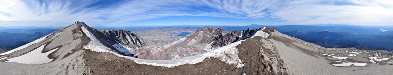 360° panorama from the summit of Mount St. Helens as seen on an early-October afternoon. In the foreground is the ice-covered crater rim.  Visible in the lower center is the lava dome. Steam rises from several dome vents. Above the dome, in the upper center, lie Mount Rainier and Spirit Lake. Mount Adams appears to the right of Rainier on the horizon as well as Mount Hood and Mount Jefferson on the far right. Also on the far right are glimpses of the Swift Reservoir, Yale Lake, Lake Merwin and the Lewis River. Climbers stand on the crater rim and are visible along the Monitor Ridge climbing route. Photo by Gregg M. Erickson