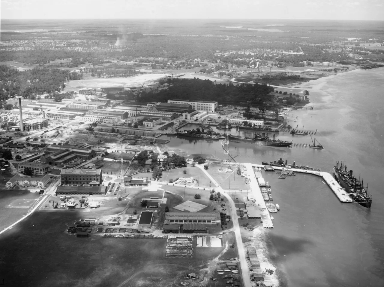 The U.S. Charleston Naval Shiyard, South Carolina (USA), preparing ships for war in 1941. The large ship on the right is probably USS Leonard Wood (AP-25), converting from an Army transport. The freighter is probably USS Hamul (AK-20), converting from a merchantman. The two two-stack destroyers at the piers are probably USS Swanson (DD-443) and USS Ingraham (DD-444) fitting out. The single-stack destroyers (2 pier side and 1 in dry dock) are probably USS Mayrant (DD-402), USS Trippe (DD-403), and USS Rhind (DD-404) in from neutrality patrol. The ships building on the ways just beyond the piers are probably USS Corry (DD-463) and USS Hobson (DD-464). Beyond them, barely visible are two more ships on another pair of ways, probably USS Beatty (DD-640) and USS Tillman (DD-641). Four of the ships afloat were commissioned between May and July 1941. The photo, taken at 300 meters, was dated 24 July 1941 and was probably taken slightly earlier. Note the Yard craft pier side in the foreground.