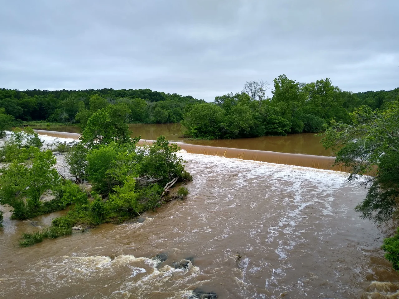 The water of the Haw River is higher than usual and is flowing over the dam in Bynum, North Carolina.