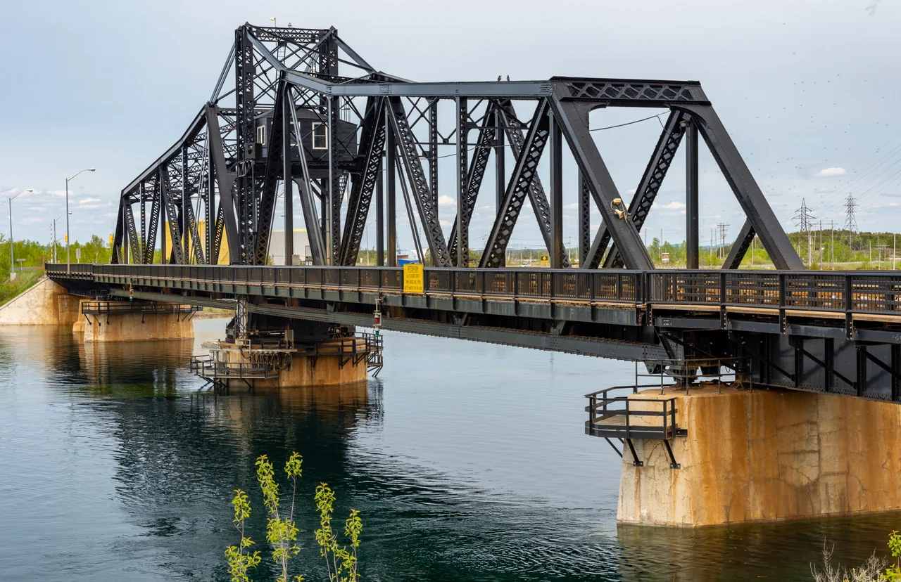 Swing bridge between Manitoulin Island and the mainland, in Little Current, Ontario, was built in 1913 by the Algoma Eastern Railway. Originally usable only by trains, it was modified in the late 1940s to allow road vehicles also to use it. The rail service was abandoned in the 1980s, and the tracks were removed in the 1990s. This view is from the southwest.