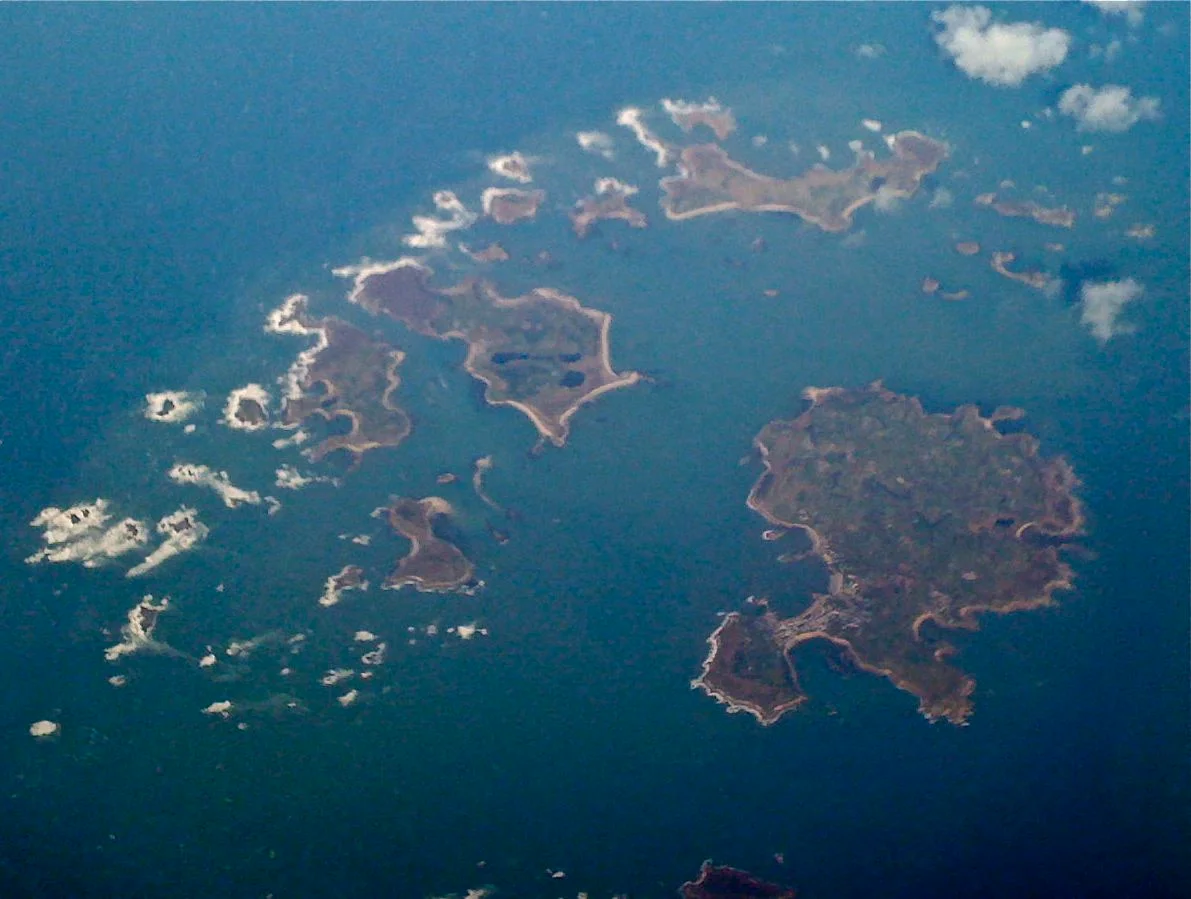 Dodgy iPhone-out-of-plane-window shot of this island group off the coast of Cornwall. Not quite complete - St Agnes and a few smaller islands are off the bottom of the shot.