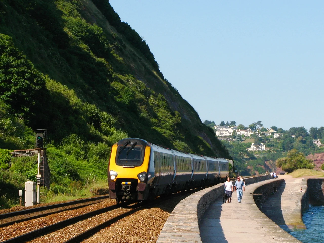 CrossCountry's 221128 runs south along the sea wall at Teignmouth in Devon, England. The footpath forms part of the 630 mile South West Coast Path.