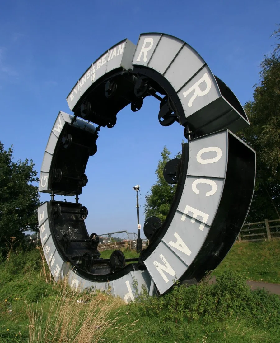 Wheel o Drams Sculpture at Maesycwmmer near Caerphilly.  Unveiled in 2000 to commemorate area's industrial history.  Sculptor was Andy Hazell.