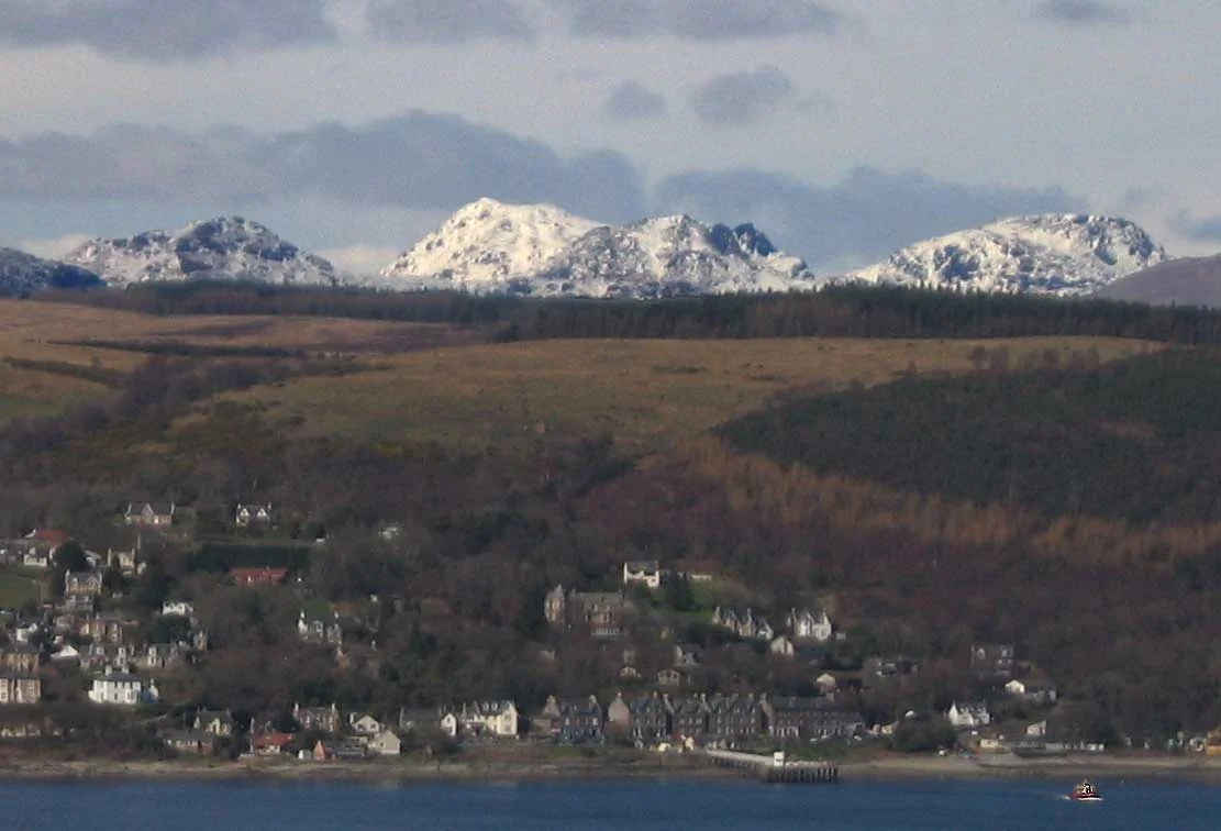 Kilcreggan on the Firth of Clyde, with the Arrochar Alps in the distance about about 29 km (18 miles) to the north of the viewpoint, seen from Tower Hill, Gourock, Scotland