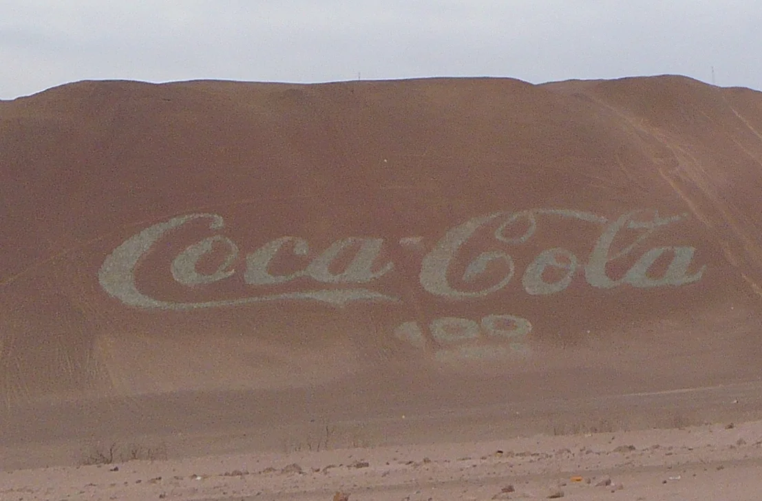 On the 100th anneversary of Coca-Cola, a giant Coca-Cola logo was built in w:Arica, Chile, with 70 000 bottles of Coca-Cola. Its dimensions are 120 by 50 m, making it the largest logo in the world.