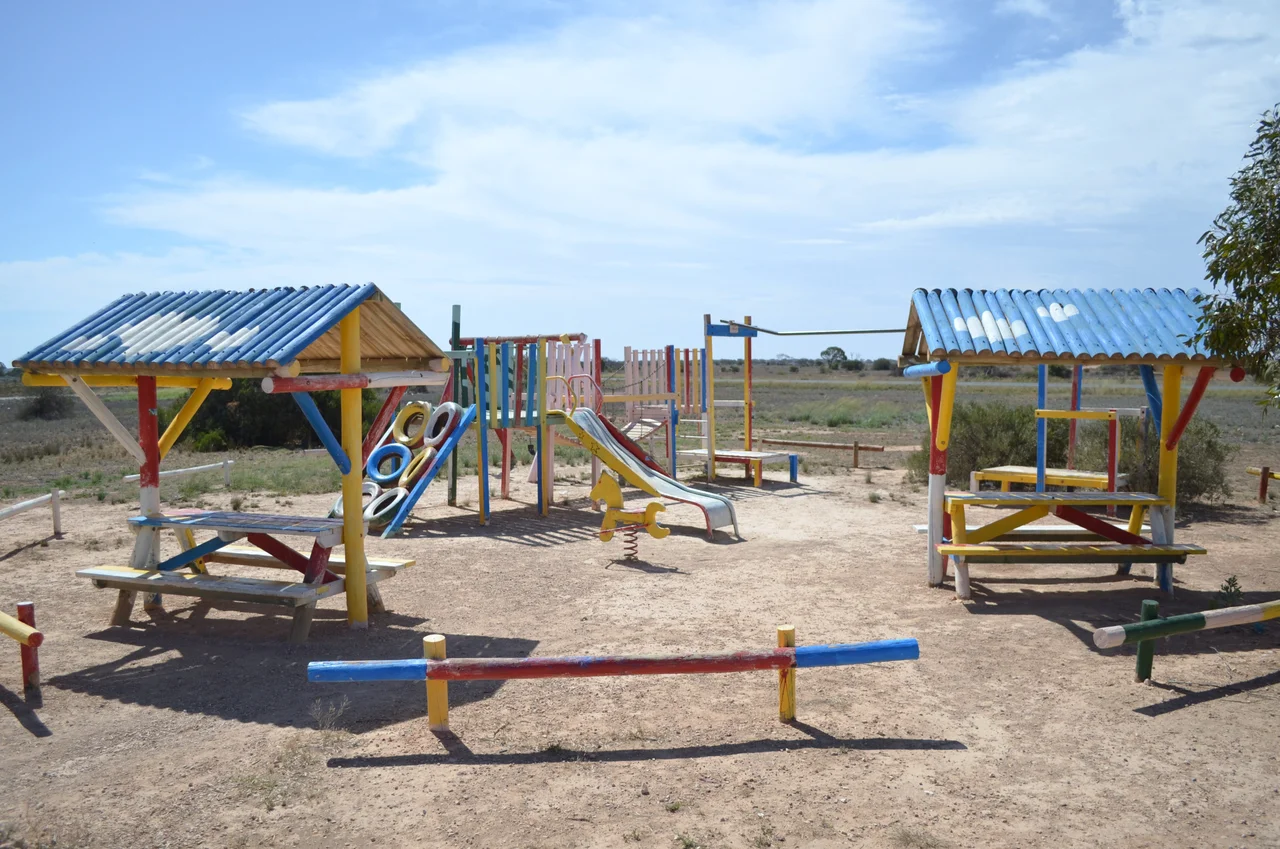 An old style playground, constructed of timber and steel, at the Cocklebiddy roadhouse, on the Nullarbor Plain, Western Australia.  Photo taken from the forecourt of the roadhouse, looking towards the Eyre Highway, which is visible in the background.