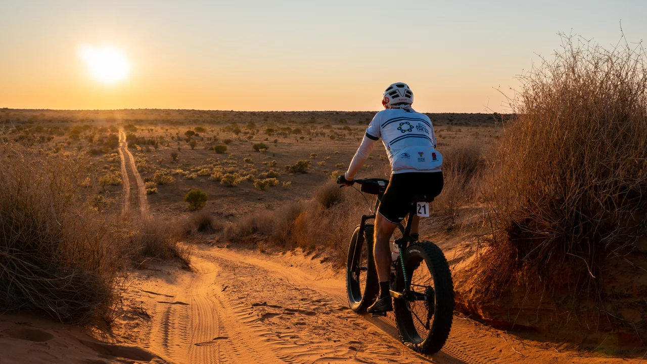 A Simpson Desert Bike Challenge competitor riding into the morning sun on day 2 of the event