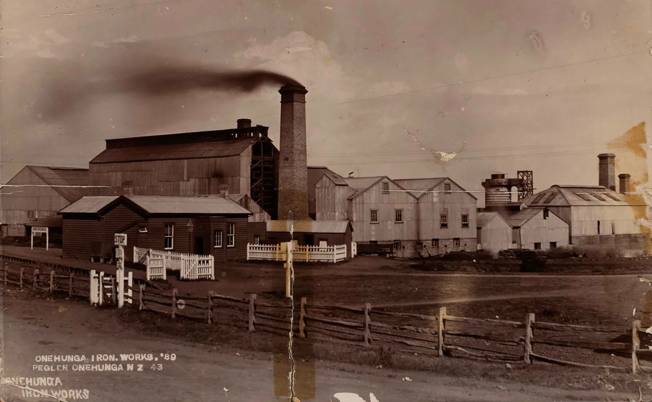 This description is taken from the Auckland Museum website:
"Image showing a large factory complex comprised of a number of tin and small weatherboard buildings. A large chimney stack made of bricks rises in the centre, with black smoke coming out of the top. A simple wooden fence runs along the length of the property, with a white sign reading 'STOP' at the gate. To the left of the image, behind a dark weatherboard building, is another white sign reading 'ONEHUNGA'. To the right of the image, behind a large metal building, is a large blast furnace and two more large brick chimneys."
The date of 1889 is based on the following; the number  " '89 " on the handwritten caption on the image; the fact that the plant is in production as evidenced by the smoke from the chimney (making it earlier than August 1895), and the fact that the blast furnace is shown (it was under construction in July 1889 and in production in June 1890).

This photograph is from the Ellen Louise McLeod collection of photographs of the Auckland Museum. The  Museum's website state that there are No Known Copyright Restrictions.