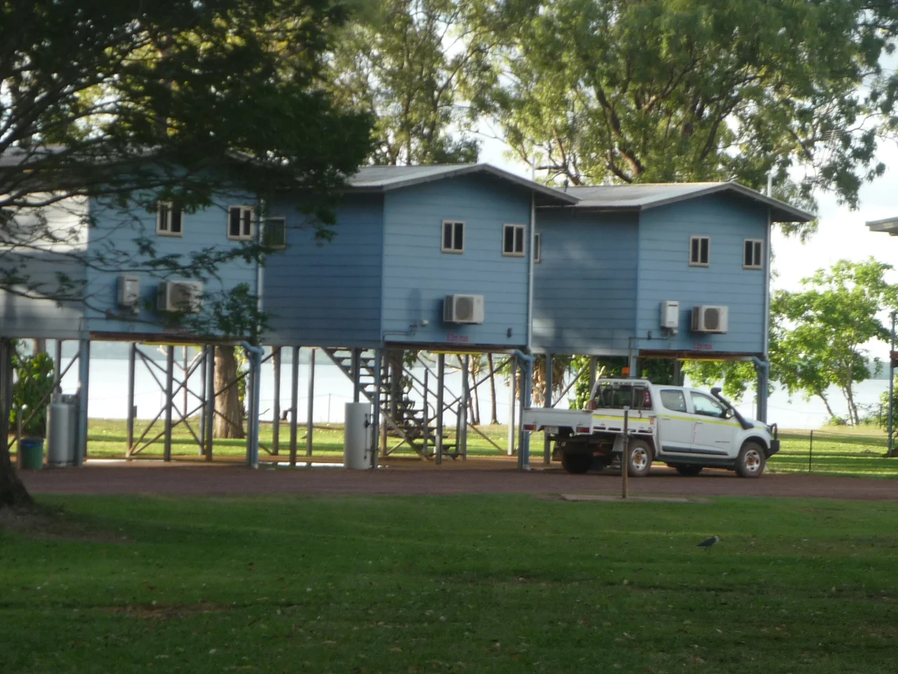 Weipa, far north Queensland, Australia.  Shows three cabins raised above the ground and a mining company four-wheel drive utility motor vehicle.  Cabins look towards the coastal Mission River.
