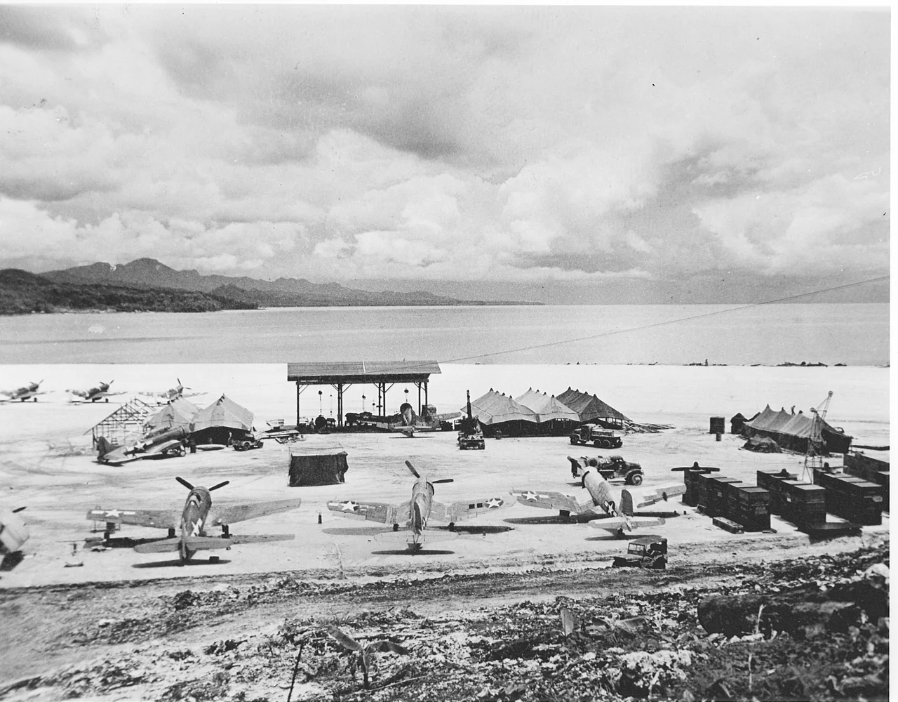 Vella Lavella airfield in the solomons on 10 December 1943. Visible U.S. Marine Corps Vought F4U-1 Corsair aircraft of Marine fighter squadrons VMF-123 and VMF-124, Grumman F6F-3 Hellcats, a Douglas SBD Dauntless, and RNZAF Curtiss Kittyhawk Mk.IV (P-40F) on the primitive runway at Vella Lavella in the Solomon Islands, which was seized in the summer of 1943 and served as a base of operations to support landings by Allied forces in the Treasury Islands and at Cape Torokina, Bougainville. The swift advance of Allied forces in the South Pacific soon bypassed Vella Lavella and the airfield ceased operations in September 1944, less than a year after the first aircraft arrived.