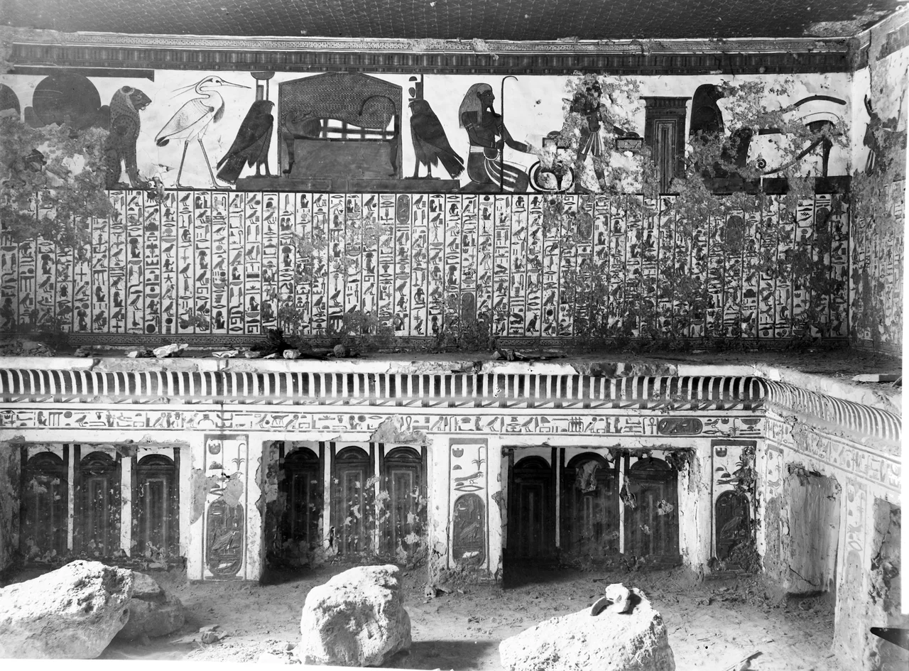 View of the antechamber, west wall, scene 3. Represented in the upper register: Atum between two lions, the Benu bird, the mummy (of Nefertari) on a bed between two falcons which represent the goddesses Nephthys and Isis. These are representations connected with the central register, which presents Spell 17 of the Book of the Dead. Below, represented on the left is a decoration composed of Djed pillars and Tit knots, while in the centre there is a cavetto cornice, with representations of sanctuaries. The presence of wall fragments on the shelf and debris on the floor could suggest that the photograph was taken shortly after the discovery of the tomb.