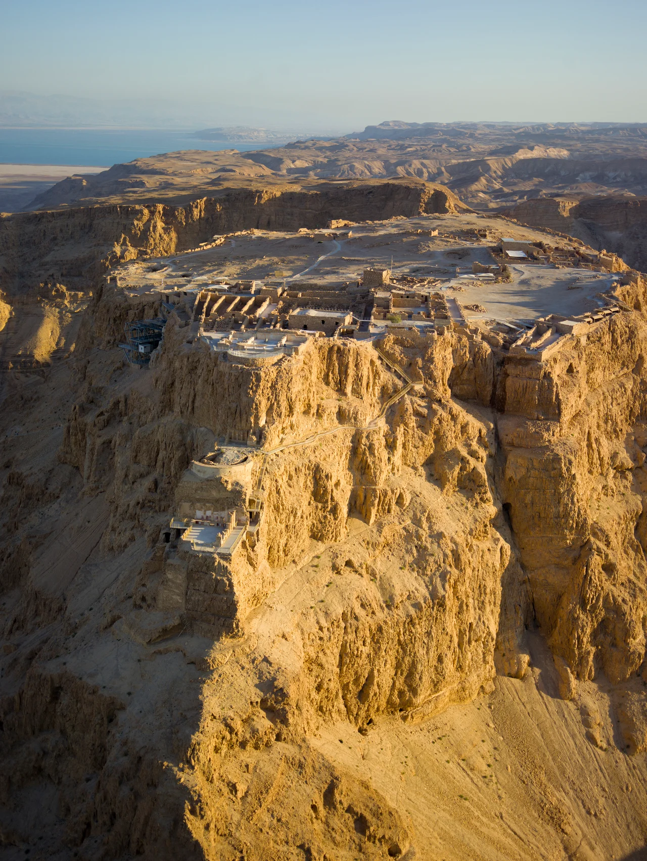 Aerial view of Masada (Hebrew מצדה), in the Judaean Desert (Hebrew: מִדְבַּר יְהוּדָה, Arabic: صحراء يهودا), with the Dead Sea in the distance.
