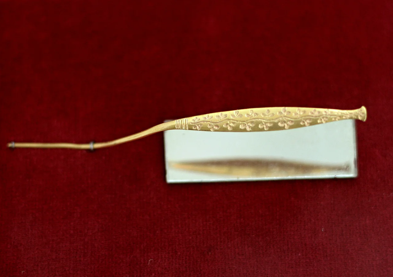 Gold needle with a relief (floral motif), on the otherside is 18 characters of Linear A script (Eteocretan in an unfamiliar language). Late Minoan I period, 1600-1425 BC. Archaeological Museum of Agios Nikolaos.