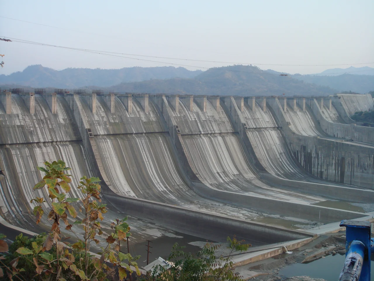 A photograph of the Sardar Sarovar Dam on the River Narmada, India, showing the principal spillway and construction underway for increasing the height from 110.64 metres to 121.92 as per clearance granted in March 2006.