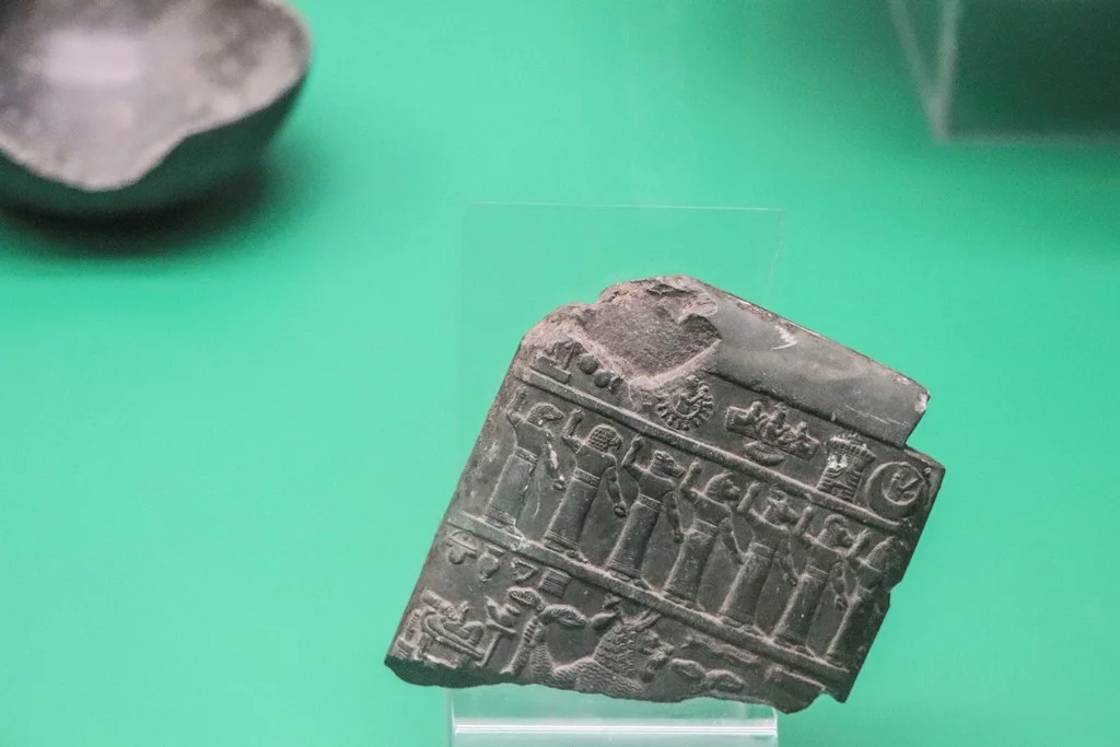 Basrah Museum, Assyrian Gallery: Stone Lamashtu plaque. Caved with symbols of gods and row of demons, the plaque was intended frighten away the demoness Lamashtu, shown in the lower register with a lion's head and grasping two-headed snakes. Neo-Assyrian period (911-612 BCE).