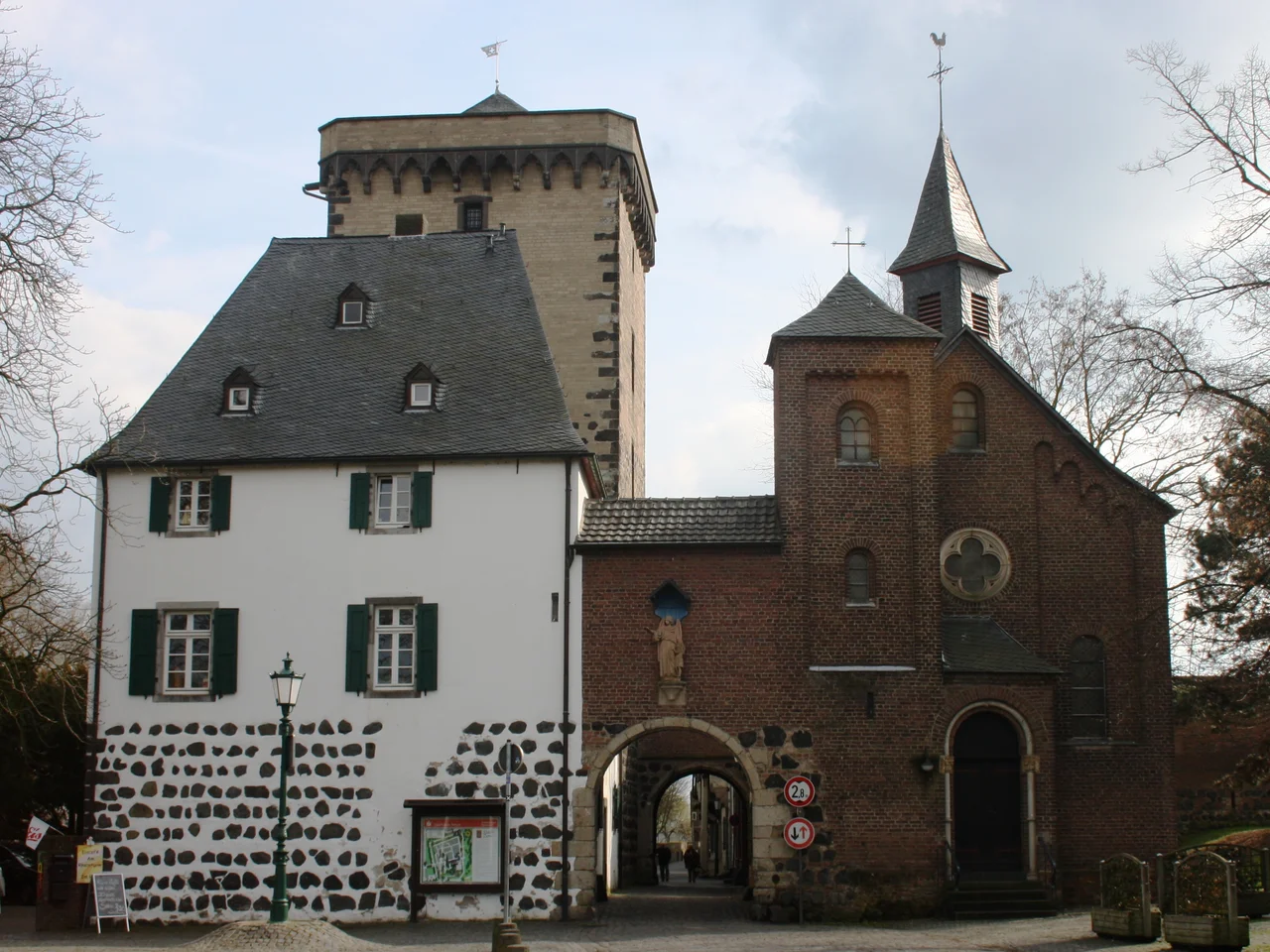 Dormagen-Zons, Germany. Rheintor city gate from north. Holy Trinity Chapel on the right