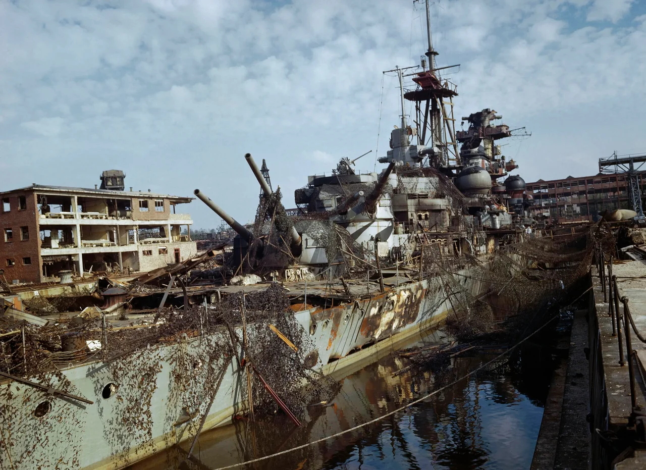 The German cruiser Admiral Hipper which was in dry dock at Kiel, Germany, when the harbour was captured by the Allies. Both the German attempts to camouflage her and the damage caused by Allied bombers can be seen.
