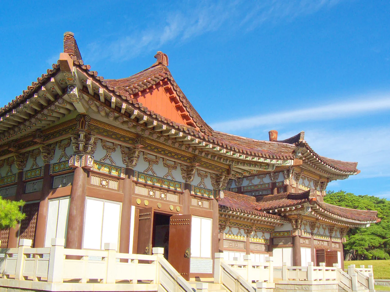 Eaves with dancheong paint at the Tomb of King Tongmyŏng, rural Pyongyang.
The king was the founder of Goguryeo, one of the Three Kingdoms (the others being Silla and Baekje).
It is the associated building in front of the funerary statues and behind the arch. (This is not at the temple complex farther away.)
The elevated lawn in the background is the platform before the tomb.